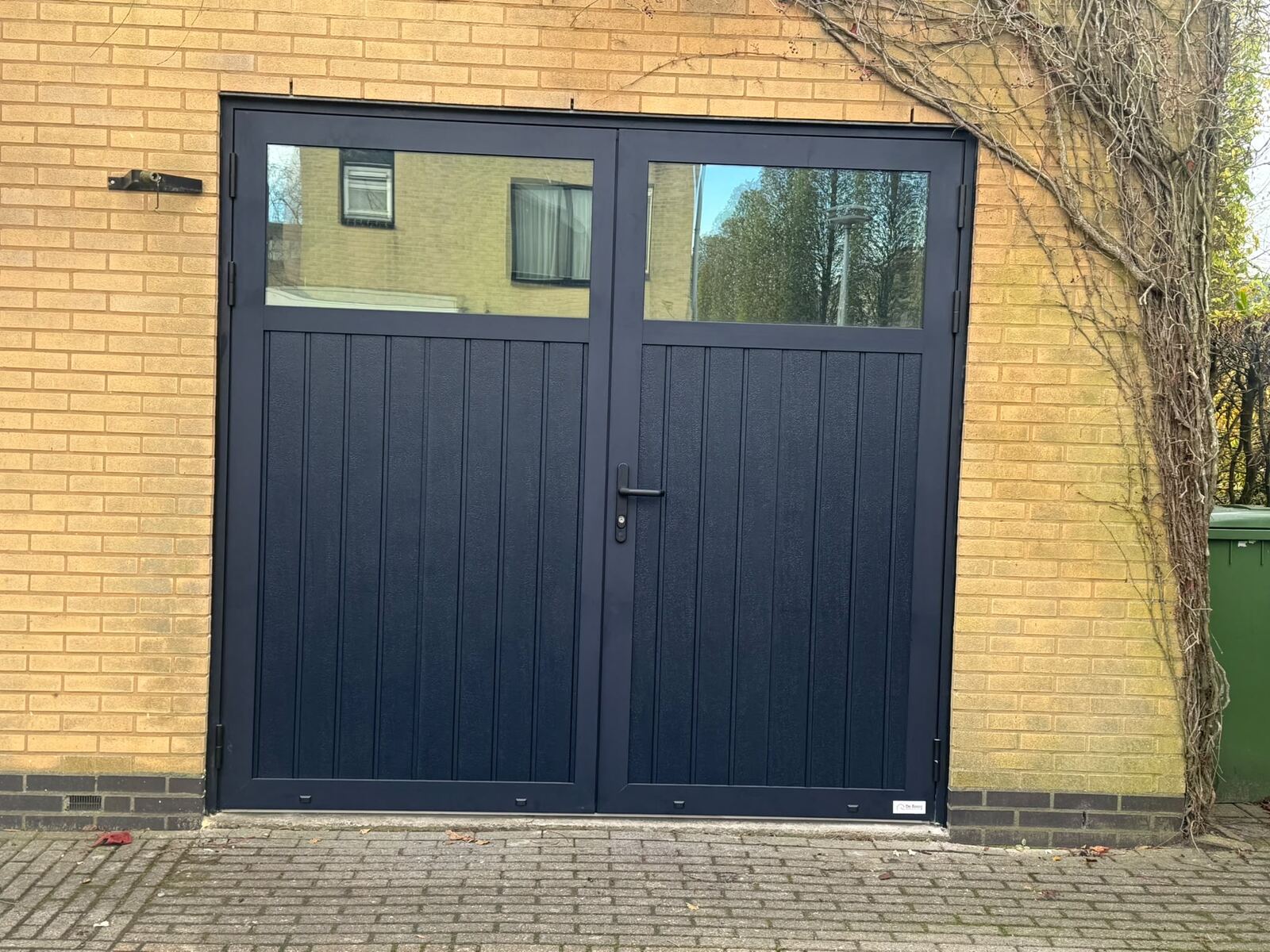 Marineblauwe openslaande garagedeur met glasstrook