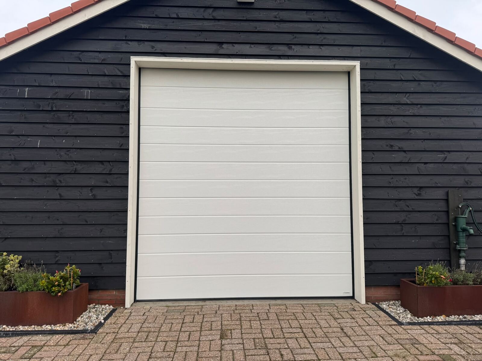 Crème garagedeur in zwart geschilderde schuur